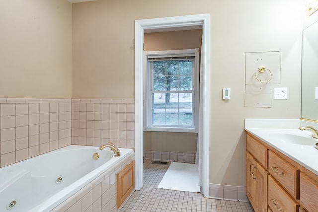 bathroom with tile patterned flooring, vanity, and tiled tub