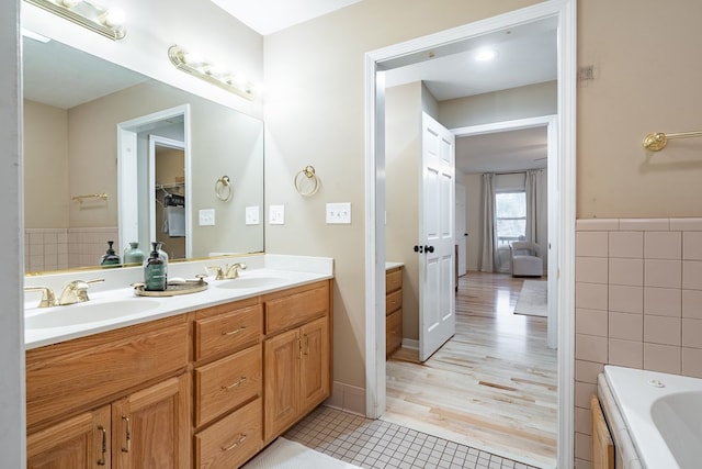 bathroom featuring tile patterned floors, vanity, a bath, and tile walls