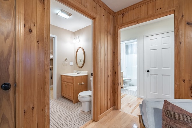 bathroom with wood-type flooring, vanity, toilet, and wood walls