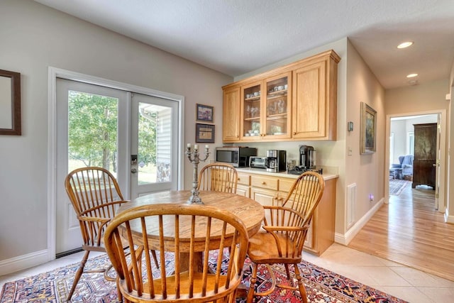 dining room with a textured ceiling, light hardwood / wood-style floors, and french doors