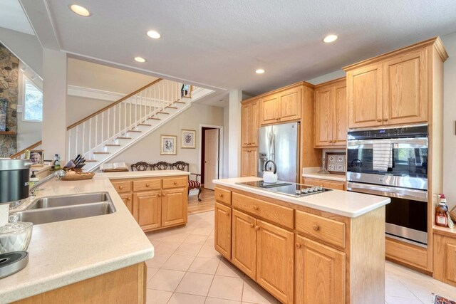 kitchen with light tile patterned floors, an island with sink, stainless steel appliances, and sink