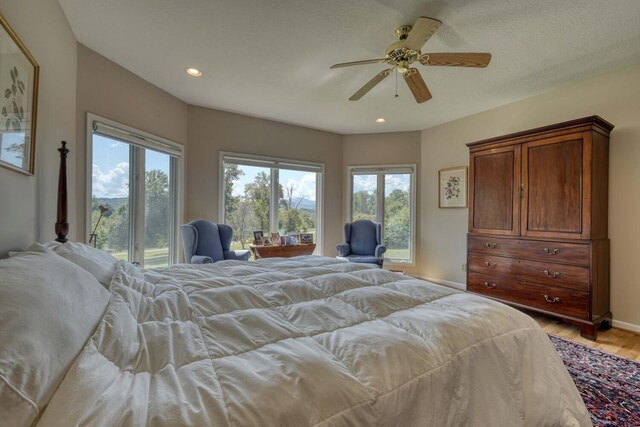 bedroom with light hardwood / wood-style floors, multiple windows, and ceiling fan