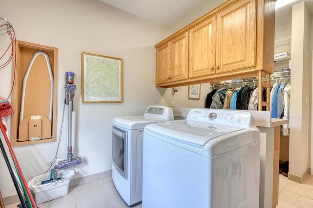 laundry area featuring cabinets, light tile patterned flooring, and separate washer and dryer