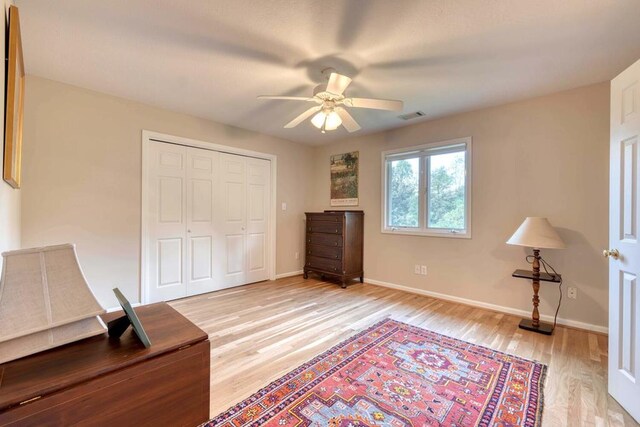 bedroom with a closet, light hardwood / wood-style floors, and ceiling fan