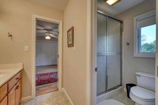 bathroom with ceiling fan, vanity, a shower with shower door, and toilet