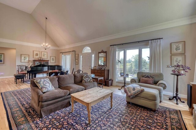 living room featuring ornamental molding, light hardwood / wood-style floors, a chandelier, and high vaulted ceiling