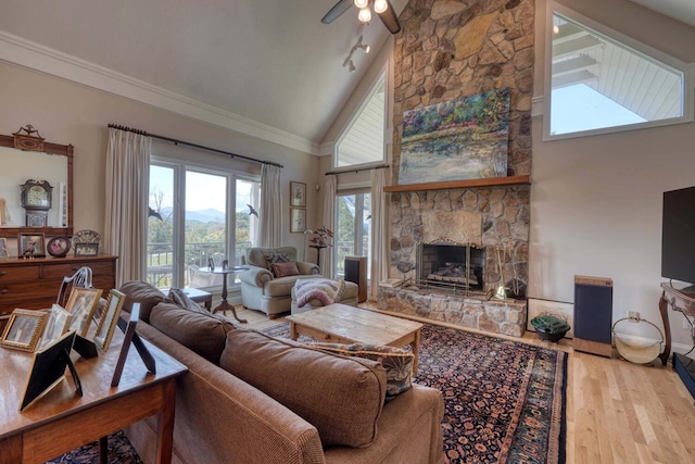 living room with ceiling fan, a fireplace, high vaulted ceiling, and light hardwood / wood-style flooring