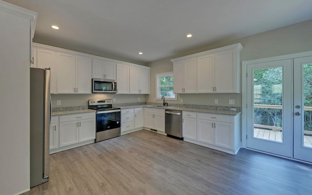 kitchen with stainless steel appliances, french doors, a sink, light wood-type flooring, and white cabinetry