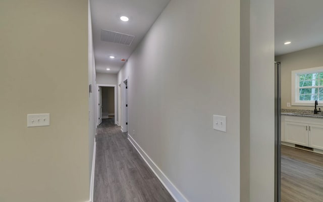 hall with recessed lighting, wood finished floors, visible vents, a sink, and baseboards