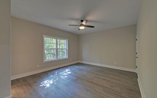empty room featuring a ceiling fan, baseboards, and dark wood finished floors