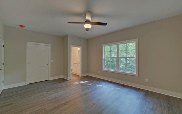 empty room with visible vents, a ceiling fan, baseboards, and dark wood finished floors