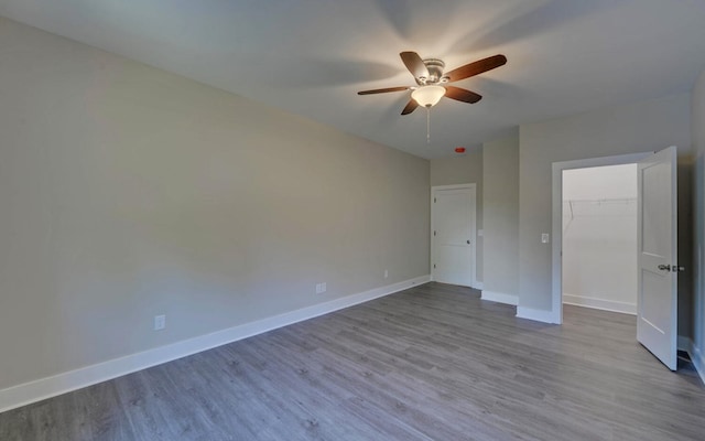 unfurnished bedroom featuring a closet, ceiling fan, a spacious closet, and light wood-type flooring