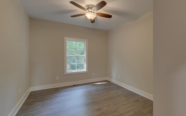 spare room featuring visible vents, a ceiling fan, baseboards, and dark wood-style flooring