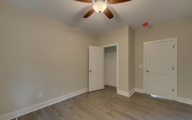 unfurnished bedroom with baseboards, wood finished floors, a closet, and ceiling fan