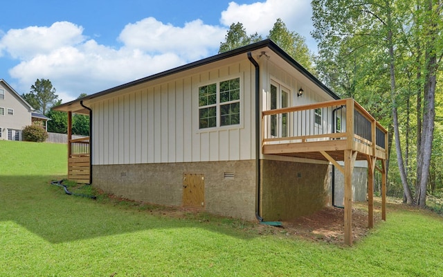 view of side of home with a wooden deck, a yard, board and batten siding, and stairway