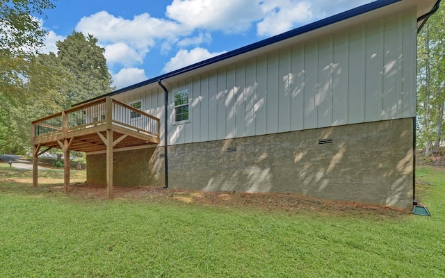 view of side of home with board and batten siding, crawl space, a wooden deck, and a yard