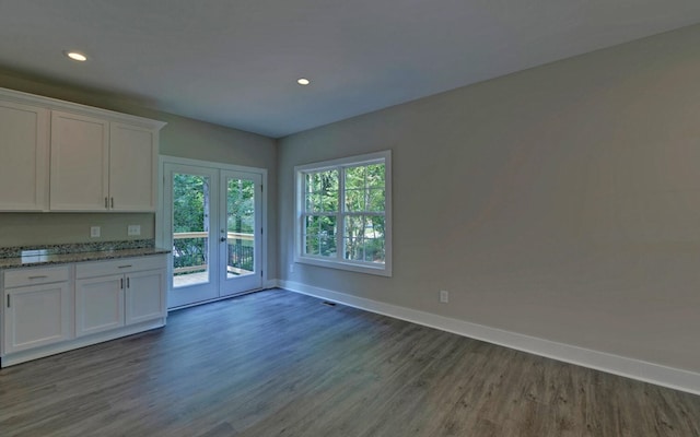 interior space with dark wood finished floors, french doors, light stone countertops, baseboards, and white cabinetry