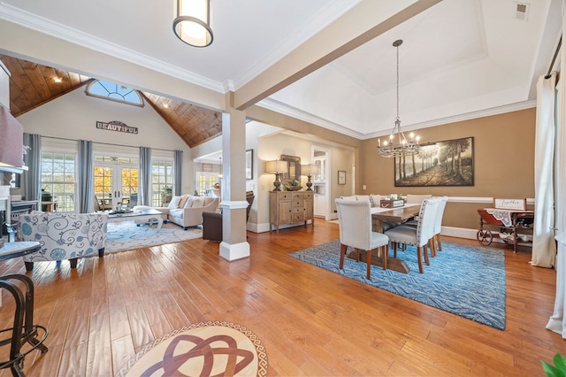 dining space featuring light wood-type flooring, high vaulted ceiling, an inviting chandelier, crown molding, and baseboards