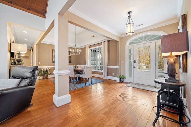 entryway featuring ornamental molding, light wood-style floors, visible vents, and a chandelier