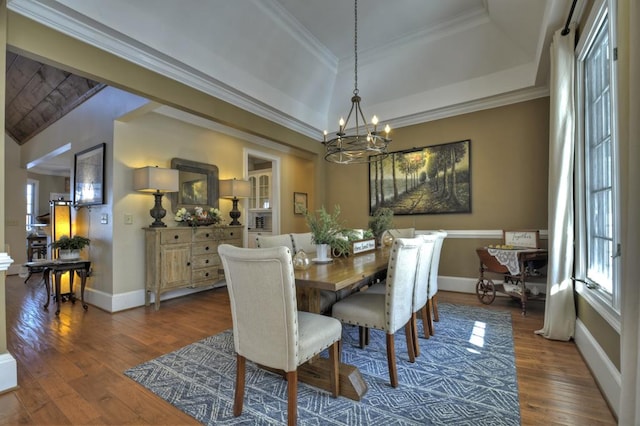 dining area with dark wood finished floors, a tray ceiling, crown molding, and a chandelier