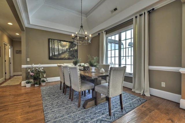 dining room with visible vents, an inviting chandelier, hardwood / wood-style floors, and crown molding