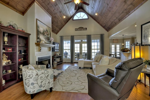 living area with a ceiling fan, high vaulted ceiling, a fireplace, hardwood / wood-style flooring, and wood ceiling