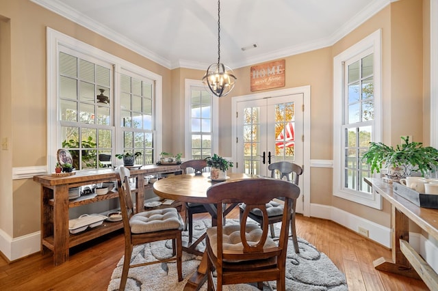 dining room featuring plenty of natural light, an inviting chandelier, ornamental molding, and light wood finished floors