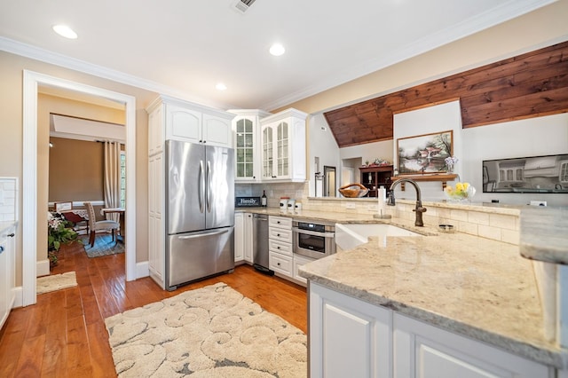 kitchen with backsplash, glass insert cabinets, appliances with stainless steel finishes, white cabinets, and a sink