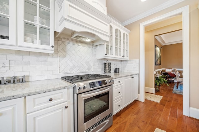 kitchen featuring light wood-type flooring, gas stove, white cabinets, crown molding, and custom exhaust hood