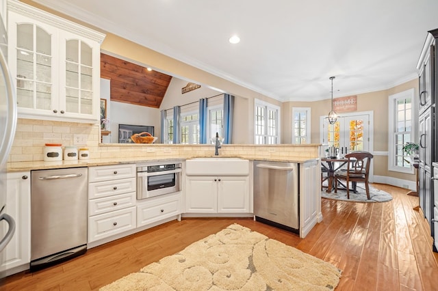 kitchen with glass insert cabinets, appliances with stainless steel finishes, light wood-style flooring, and decorative backsplash