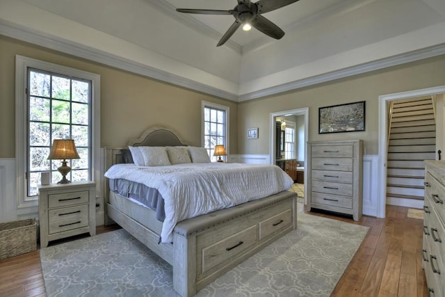 bedroom with wainscoting, crown molding, light wood-style floors, and ceiling fan