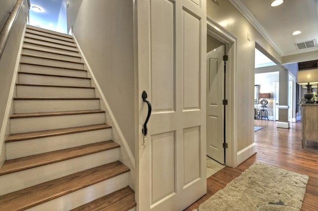 stairway with visible vents, baseboards, ornamental molding, recessed lighting, and wood finished floors