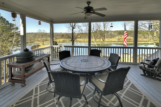 wooden deck featuring outdoor dining area, ceiling fan, and a water view