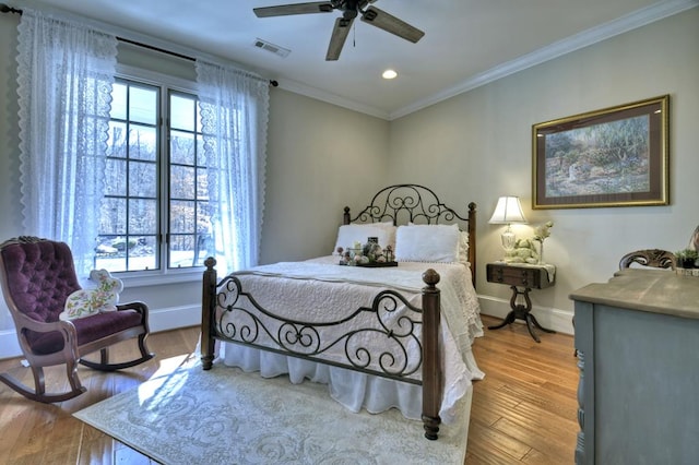 bedroom with visible vents, wood finished floors, crown molding, baseboards, and ceiling fan