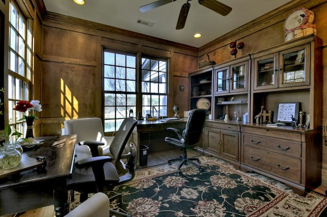 office area with visible vents, wood finished floors, wooden walls, and ceiling fan