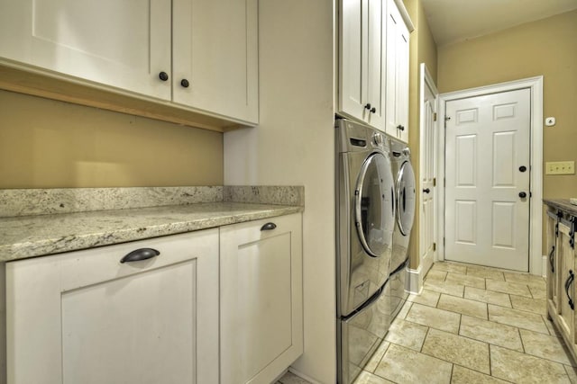 laundry area featuring cabinet space, washing machine and dryer, and stone finish floor