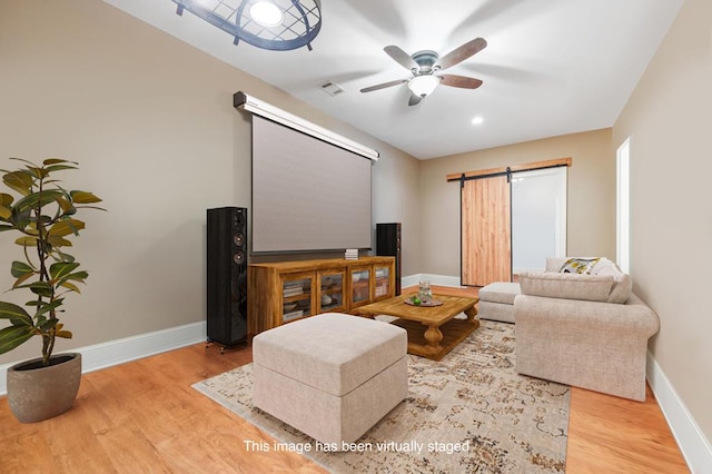 home theater room with a barn door, wood finished floors, and baseboards