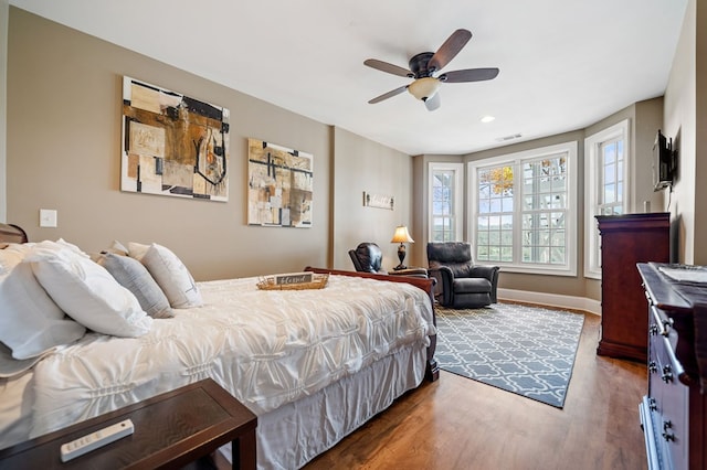 bedroom with visible vents, a ceiling fan, baseboards, and wood finished floors