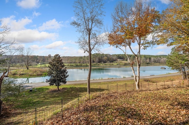 property view of water featuring fence and a forest view