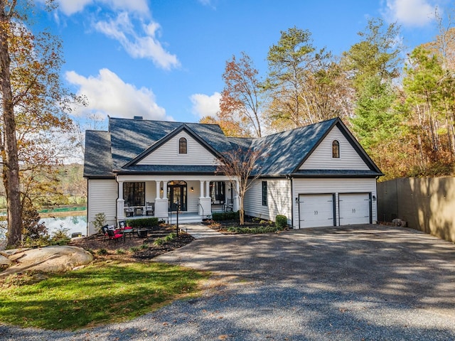 view of front of home with gravel driveway, a porch, an attached garage, and fence