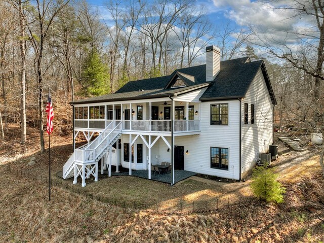 back of house featuring a patio, stairway, a sunroom, ceiling fan, and a chimney