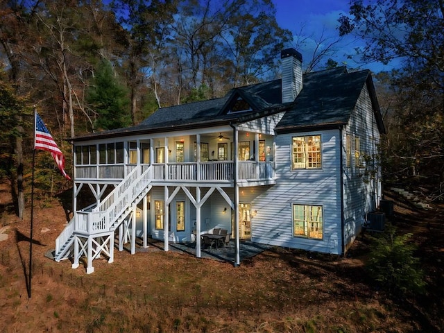 back of house with a sunroom, a chimney, stairs, central air condition unit, and a patio area