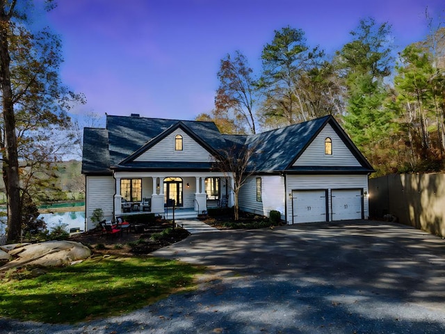 view of front of house featuring an attached garage, fence, covered porch, and driveway