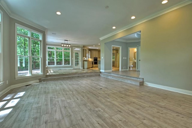 unfurnished living room featuring crown molding, light hardwood / wood-style flooring, and a chandelier