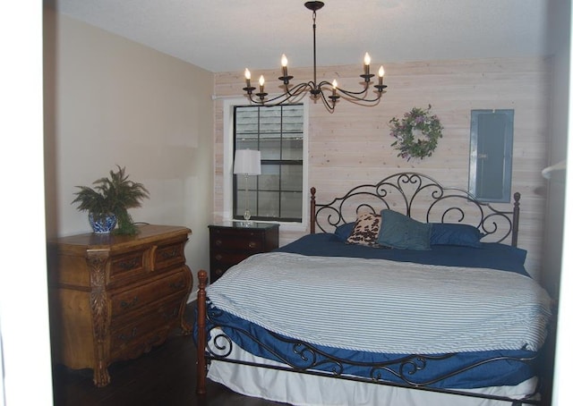 bedroom featuring a notable chandelier, wooden walls, hardwood / wood-style flooring, and electric panel