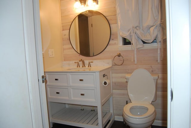 bathroom with vanity, wood walls, and toilet