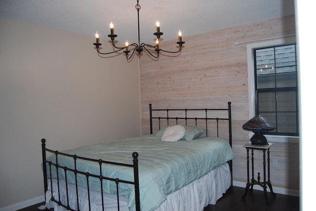 bedroom featuring wood-type flooring, wood walls, and an inviting chandelier