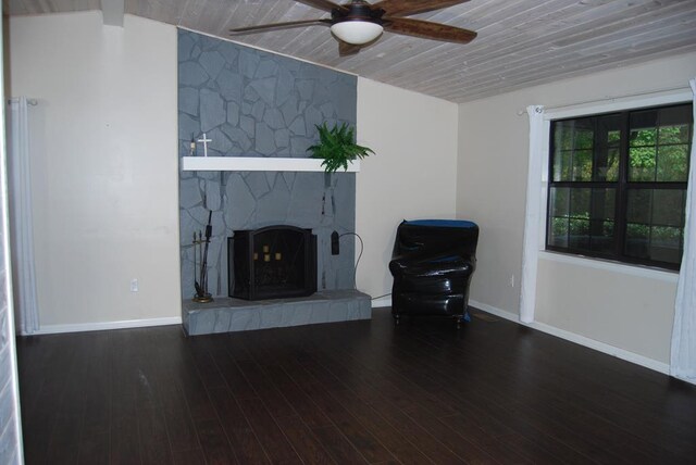 unfurnished living room with ceiling fan, wooden ceiling, dark wood-type flooring, and a stone fireplace