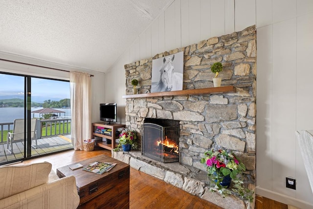 2793 Hidden Valley Rd, Hiawassee, GA 30546 - living area featuring a stone fireplace, vaulted ceiling, wood finished floors, and a textured ceiling