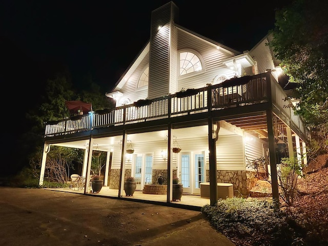 back house at twilight featuring central AC unit, french doors, and a patio